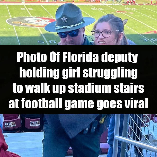Photo Of Florida deputy holding girl struggling to walk up stadium stairs at football game goes viral
