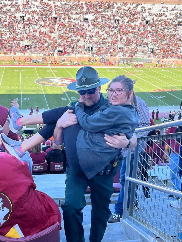 Photo Of Florida deputy holding girl struggling to walk up stadium stairs at football game goes viral - picture 2