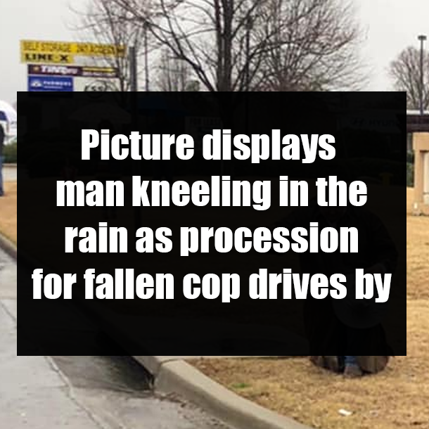 Picture displays man kneeling in the rain as procession for fallen cop drives by